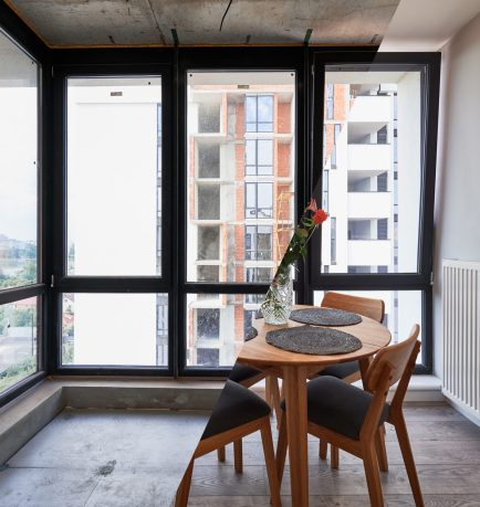 Photo collage of living room with large panoramic window before and after renovation. Old apartment with heating radiator and new renovated flat with flowers on table and elegant interior design.