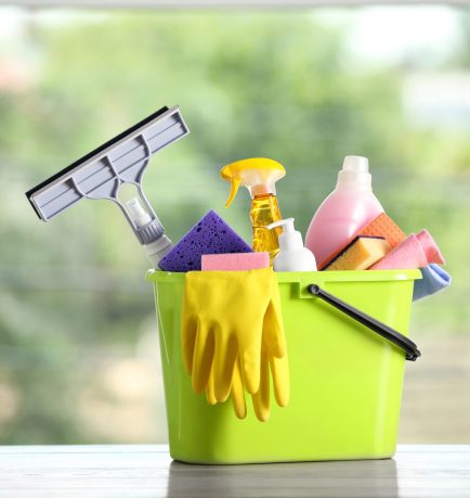 Light green bucket with cleaning products on wooden table indoors